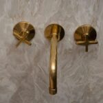 Wall mounted bath faucet in unlacquered brass